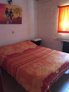a bedroom with a bed with a red blanket at Cabañas y Posada La Vertiente in Los Reartes