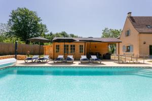 una piscina con sillas y sombrillas junto a una casa en Luxury 3 Bed Home with Heated Swimming Pool Air Con and Boules Pitch, en Salignac