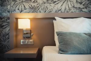 サン・テギュルフにあるオテル ル カタローニャのベッドルーム1室(ランプ、枕付)
