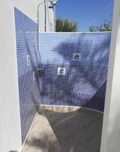 uma casa de banho com um chuveiro de azulejos azuis e um WC. em Delphini Studios em Kefalos