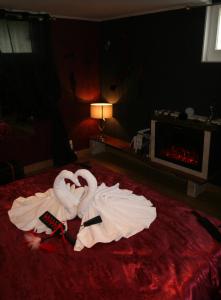 twee zwanen gemaakt van handdoeken op een bed bij BDC Le Boudoir de Cormelles in Cormelles