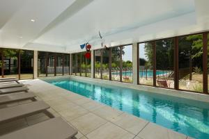 a swimming pool with chaise lounge chairs and windows at Les Nomades Beaune in Beaune