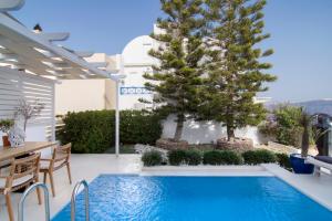 a pool with a tree and a table and chairs at Santorini Secret Suites & Spa, Small Luxury Hotels of the World in Oia