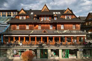 a large wooden building with people sitting on a balcony at Hotel Sabała in Zakopane