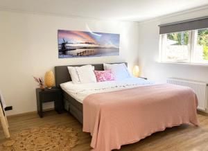 een slaapkamer met een groot bed en een roze deken bij B&B Hof ter Lemferdinge in Paterswolde