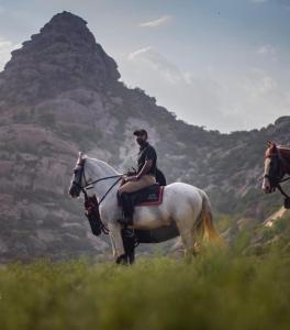 a man riding a white horse in a field at SUJÁN JAWAI - Relais & Chateaux in Pāli