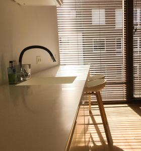 a kitchen with a counter with a sink and a stool at ROOOm Kortrijk in Kortrijk