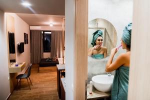 a woman brushing her teeth in front of a bathroom mirror at Glam Boutique Apartments - Thessaloniki Heart in Thessaloniki