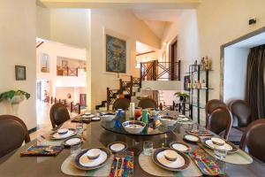 a dining room with a table with chairs and a table at StayVista's Shantam House - Dive into relaxation with a pool and tennis lawn in Lonavala