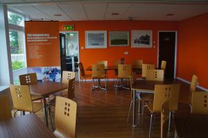 comedor con mesas, sillas y paredes de color naranja en YHA Conwy en Conwy