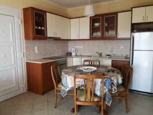 een keuken met een tafel en stoelen en een koelkast bij Nostos - Psili Ammos Apartments in Psilí Ámmos