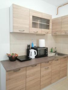 a kitchen with wooden cabinets and a microwave at Apartman River in Sremska Mitrovica