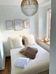 1 dormitorio con 1 cama blanca grande con lámpara de araña en L'amiral n3 T2 nouvelle ville ByLocly, en Lorient