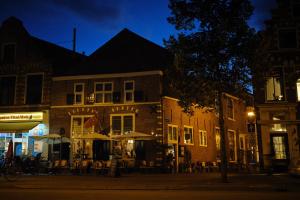 a building with tables and umbrellas on a street at night at Hôtel Frenchie in Haarlem