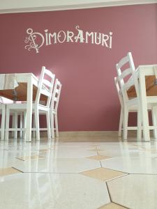 uma mesa e cadeiras contra uma parede rosa com uma placa em Dimoramuri B&B em Catânia