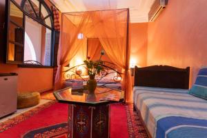 ein Schlafzimmer mit einem Bett und einem Tisch mit einer Vase darauf in der Unterkunft Riad Losra in Marrakesch