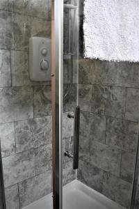La salle de bains est pourvue d'une douche avec une porte en verre. dans l'établissement The Little Pheasant Apartment Ironbridge Gorge, à Broseley