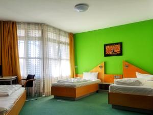 Habitación con 2 camas y pared verde. en Sportschule Oberhaching, en Oberhaching