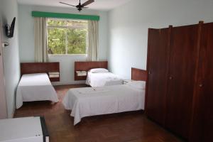 um quarto com três camas e uma janela em Hotel do CEE em Viçosa