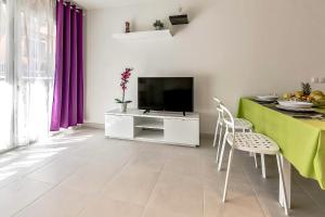 sala de estar con TV y mesa con sillas en Hortensia Suites Apartments ,Los Cristianos en Los Cristianos