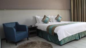 a bedroom with a bed and a blue chair at Urban Bliss Hotel in Kabwe