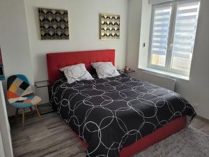sypialnia z czarno-białym łóżkiem i krzesłem w obiekcie charmant appartement confort déco neuf , proche Epinal et Lac de Bouzey w mieście Uxegney