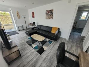 a living room with a black couch and a table at charmant appartement confort déco neuf , proche Epinal et Lac de Bouzey in Uxegney