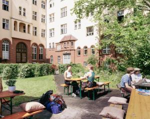 eine Gruppe von Personen, die an Tischen im Innenhof sitzen in der Unterkunft Three Little Pigs Hostel - Your Berlin Castle in Berlin