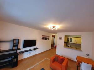 ein Wohnzimmer mit einem orangenen Stuhl und einem Flachbild-TV in der Unterkunft BLUE EYES SAILORS in Kotor