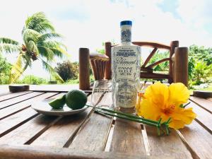 una bottiglia di alcol seduta su un tavolo con lime e fiori di appartement privé ECO-RESPONSABLE, magnifique vue sur la mer des Caraibes et jardin clos, WiFi, à 2mn de la plage a Sainte-Luce