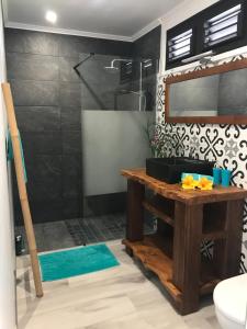 appartement privé ECO-RESPONSABLE, vue sur la mer des Caraibes et jardin clos, WiFi, à 2mn de la plage في سانت لوسي: حمام مع دش مع طاولة خشبية