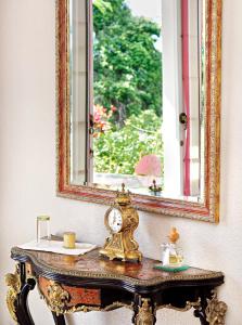 a gold clock on a table under a mirror at La Maison d'Edith in La Montagne