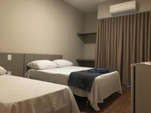 a hotel room with two beds and a window at Skala Park Hotel in Sertãozinho