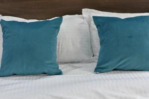 a bed with blue pillows and white sheets at Ohm Village Inn(OVI) in Kitui