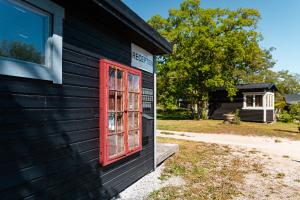 ein rotes Fenster auf der Seite eines schwarzen Gebäudes in der Unterkunft Fårösunds Semesterby in Fårösund