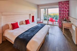 a bedroom with a large bed with a desk and a window at Hôtel Miléade La Frégate - Bidart in Bidart