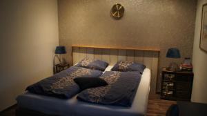 sypialnia z łóżkiem z poduszkami i zegarem na ścianie w obiekcie Ferrum Ferrum w mieście Valkenburg