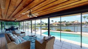 a living room with a ceiling fan and a pool at Waterfront Tip Lot Treasure w/ Southern Sunshine in Henry Key