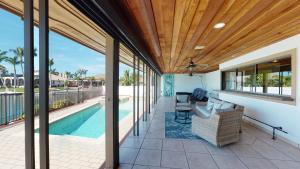 an outdoor patio with a pool and a wooden ceiling at Waterfront Tip Lot Treasure w/ Southern Sunshine in Henry Key +27 photos