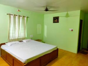 a bedroom with a bed in a room with green walls at Nature Camp Bhitarkanika Retreat in Righāgarh