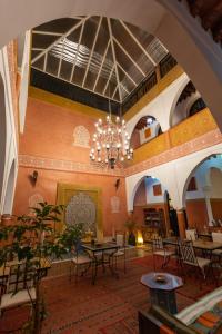 Habitación grande con mesas, sillas y lámpara de araña. en Riad Losra, en Marrakech