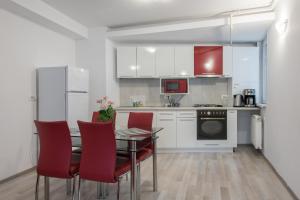 a kitchen with a dining table and red chairs at Shabbat Apartments in Bucharest
