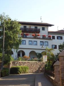 un edificio blanco con flores rojas en los balcones en Gasthof zum Roessl, en San Genesio Atesino