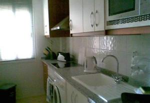 a kitchen with a sink and a microwave at 2 bed apartment with pools and spa in Vera