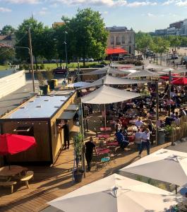 Une foule de gens assis aux tables et aux parasols dans l'établissement Eklo Bordeaux Centre Bastide, à Bordeaux