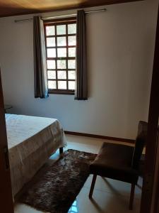 a bedroom with a bed and a chair and a window at Casa Charme de Lençois in Lençóis