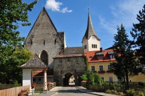 an old building with a gate and a church at Pension Geissler-Reicher in Oberwölz Stadt