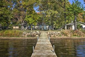a wooden dock in front of a house on a lake at Waterfront Onamia Retreat with Dock and Fire Pit! in Onamia