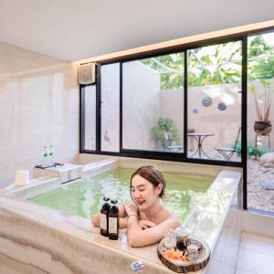 a woman sitting in a bath tub with a plate of food at Tree Tara hotel -- SHA Plus in Lampang