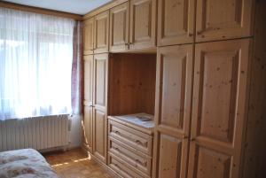 1 dormitorio con armarios de madera, 1 cama y ventana en Appartamento Anna & Gino, en Sappada